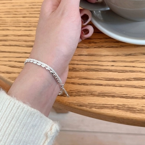 Double-layered S925 silver bracelet with star beads on a woman's wrist in a cafe