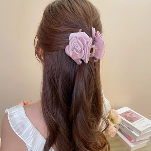 Dettaglio di un grande fermaglio per capelli a fiore in raso rosa antico su modella