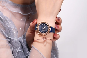 Gros plan d'une montre élégante en or rose et d'un bracelet nœud cœur au poignet