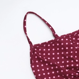 Dettaglio della spallina regolabile su abito rosso a pois con cuciture e trama