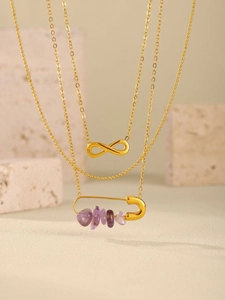 Détail de collier doré multicouche avec pendentif infini et épingle à pierre violette
