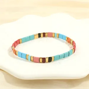 Detail of bohemian Tila bead bracelet with colorful enamel tiles on white ceramic plate