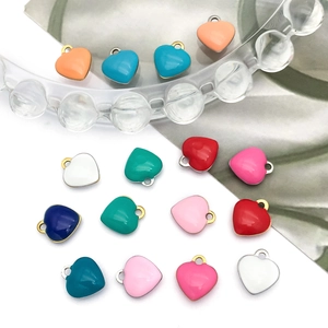 Macro view of colorful heart-shaped enamel charms with metal loops for DIY jewelry making