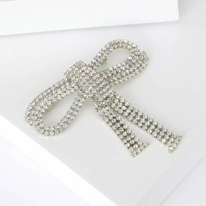 Close-up of a silver bow brooch featuring faceted rhinestones on minimalist blocks