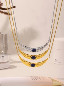Detail of crescent moon pendant with hammered gold texture and inlaid blue lapis lazuli