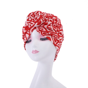 Detail of red and white knotted turban hat with bohemian knit texture on a model