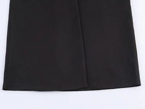 Detailed view of the smooth black fabric texture and hem stitching on a street style coat