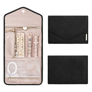 Macro view of portable jewelry organizer with quilted black texture and beige compartments