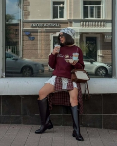 Détail du sweat-shirt bordeaux avec broderie Rich et des bottes en cuir noir