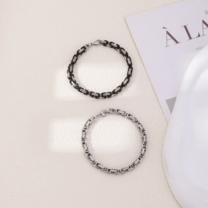 Detailed view of black and silver Byzantine weave bracelets on a textured background