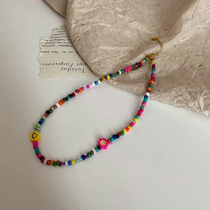 Detail of colorful bohemian seed bead necklace with smiley face charms and gold chain