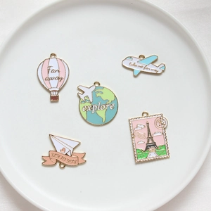 Travel themed enamel charms set with hot air balloon and Eiffel Tower on white tray