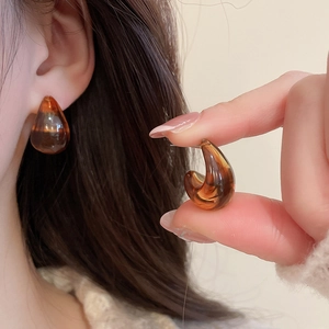 Detail of amber acrylic C-shaped earrings with faux tortoiseshell pattern and silver pins