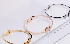Detail of three butterfly bangles in gold, rose gold and silver finishes with hinge