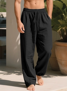Dettaglio dei pantaloni larghi neri da uomo con coulisse e texture in lino traspirante