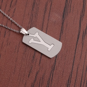 Collier avec pendentif en acier inoxydable poli et lettre Y sur fond de bois brun