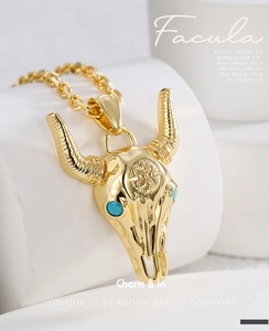 Detail of a gold-plated bull skull pendant with turquoise inlay on a white background