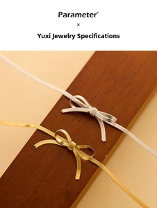Macro detail of gold and silver bow necklaces with textured snake chains on wood