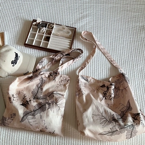 Detail of pink and beige canvas tote bags with elegant black leaf prints and large capacity