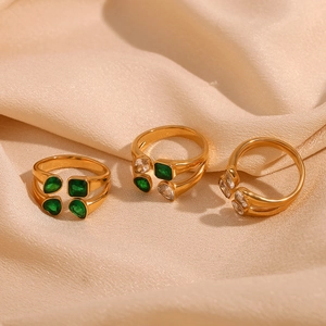 Detailed view of dual-layer 18K gold plated rings with green and white zircons on silk
