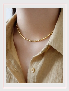 Close-up of minimalist 18K gold plated titanium oval bead necklace on model