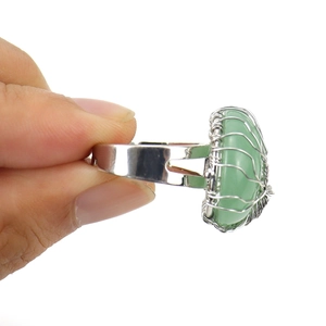 Detailed close-up of handmade silver wire wrapped ring with green gemstone on hand
