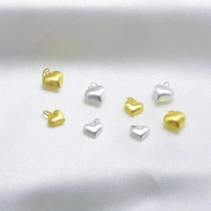 Macro shot of 925 silver heart pendants in gold and silver with brushed matte texture