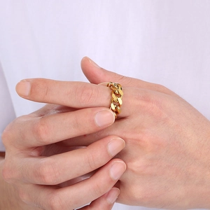 Close-up of a golden Cuban link chain ring worn on a finger in a street style look