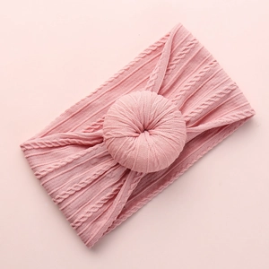 Detail of pink knitted baby headband with soft cable texture and central round knot ball