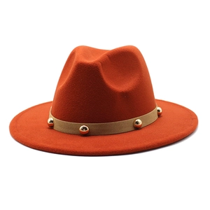 Detail of rust red fedora hat with light brown suede band and gold spherical studs