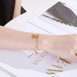 Polished gold titanium steel bangle featuring a hollow smiley face charm worn on a wrist