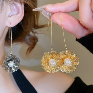 Détail des boucles d'oreilles fleur plaquées or 18 carats avec zircon et crochet long
