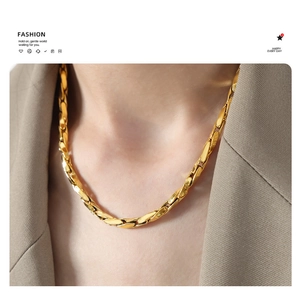 Detail of gold-plated thick chain necklace with faceted texture on a chic suit model
