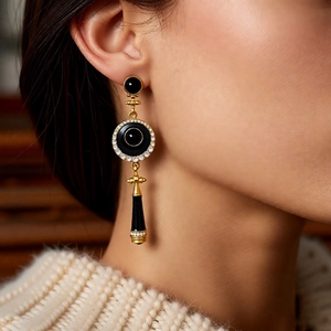 Close-up of vintage gold drop earrings with black enamel and crystals on model
