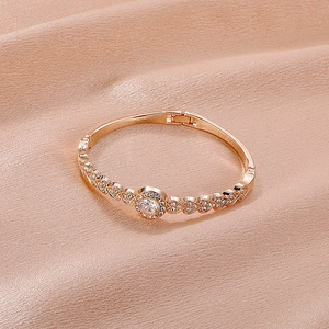 Rose gold heart bangle with crystals placed on premium champagne satin background