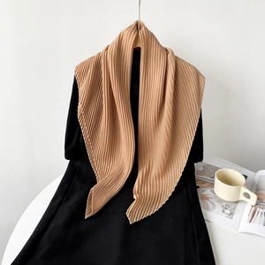 Detailed texture of pleated solid khaki silk-like scarf draped over black clothing
