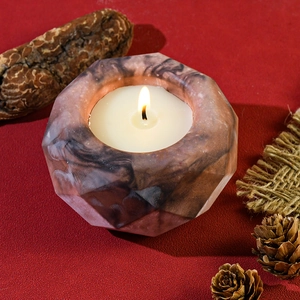 Octagonal marble resin candle holder with lit candle and rustic pine cone decor