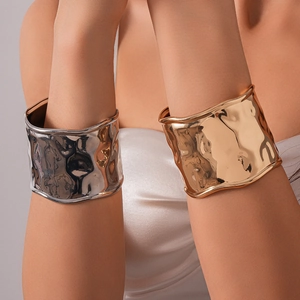Détail de larges bracelets métalliques en or et argent avec finition martelée