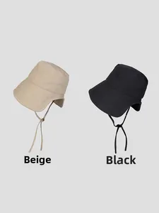 Detail of beige and black wide-brim sun hats showing adjustable chin straps and cotton texture