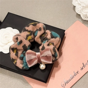 Pink leopard knit scrunchie with velvet bow and pearl charm on a stylish gift box