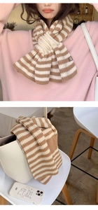 Detail of a brown and white striped knitted scarf showing wool blend texture and cross design