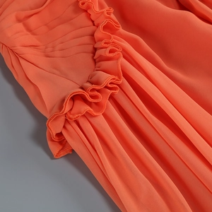 Dettaglio del tessuto in chiffon arancione con bordi a balze e trama plissettata