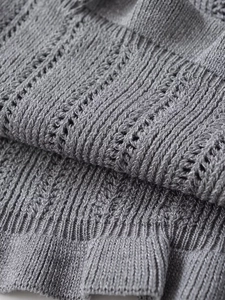 Detailed macro view of grey knit cardigan fabric with vertical stripes and hollow out patterns