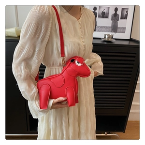 Detail view of red horse-shaped crossbody bag with adjustable strap on white dress