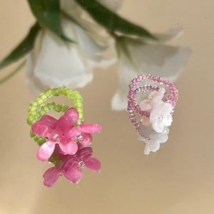 Detailed view of pink and green resin flower beaded rings on a reflective mirror base
