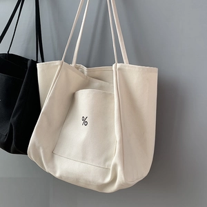 Detailed view of minimalist canvas tote bags with signature percent logo and front pocket