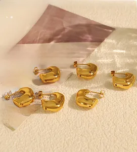 Detail of chunky gold-plated C-shape earrings with a polished finish on a Vogue magazine