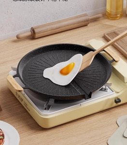 Detail of round non-stick grill pan with oil-drain grooves and wooden handles