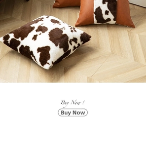 Detail of cow print faux fur and brown leather patchwork pillowcase on wooden floor