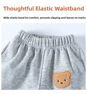 Detail of elastic waistband on grey knit kids pants with a cute teddy bear patch